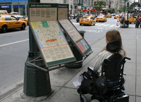 mujer en silla de ruedas leyendo en un panel de informacionesación en veredas