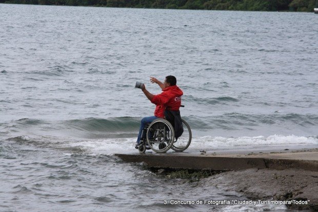 un hombre en silla de ruedas pesca a orillas de un lago