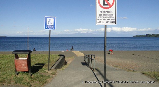 lago llanquihue y en primer plano las señalizaciones d eestacionamientos para personas con discapacidad y letrero de acceso a la playa