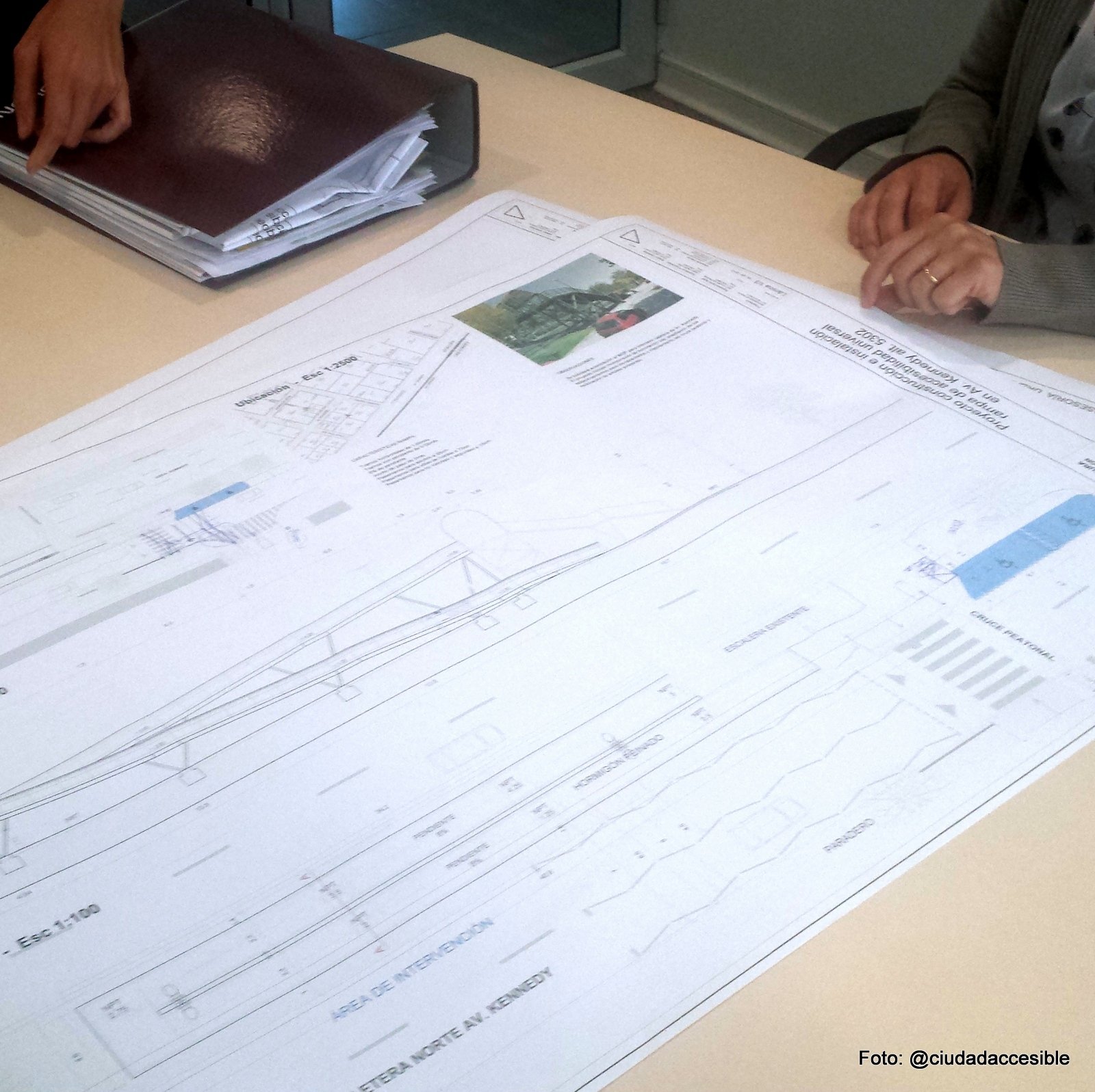 Plano desplegado sobre una mesa y manos de personas que lo están estudiandoProyecto original rampa a pasarela peatonal Parque Arauco