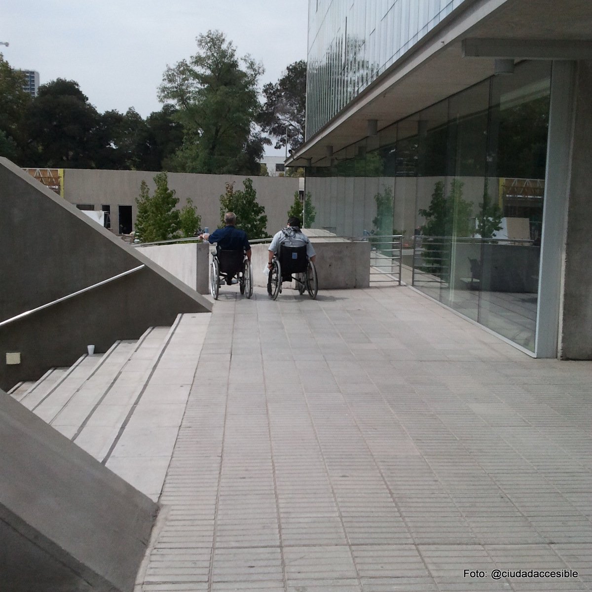 dos personas en silla de ruedas saliendo de un edificio