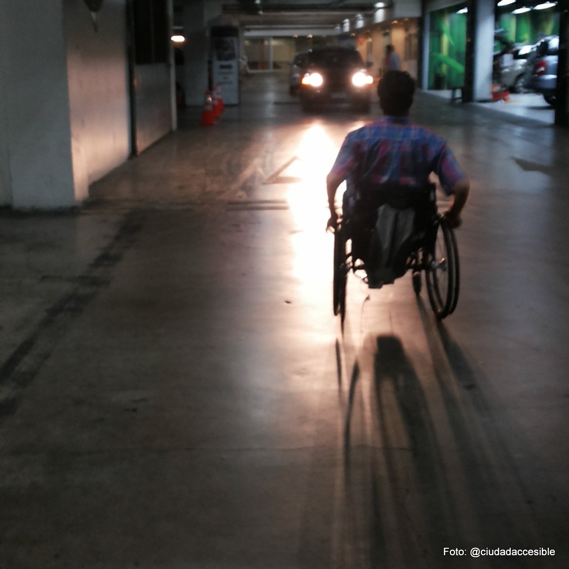 persona en silla de ruedas circulando en un estacionamiento subterraneo