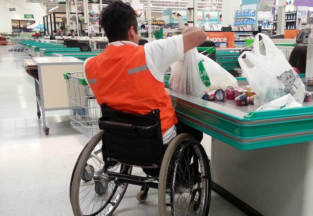 persona en silla de ruedas trabajando como empaquetador de supermercado