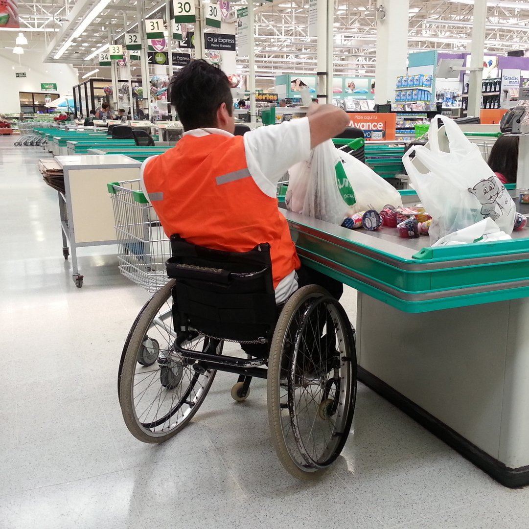 persona en silla de ruedas trabajando como empaquetador de supermercado