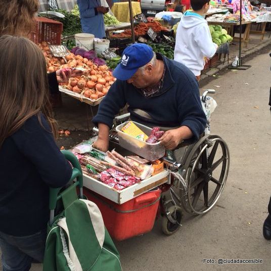 persona en silla de ruedas vendiendo mercadería en una feria