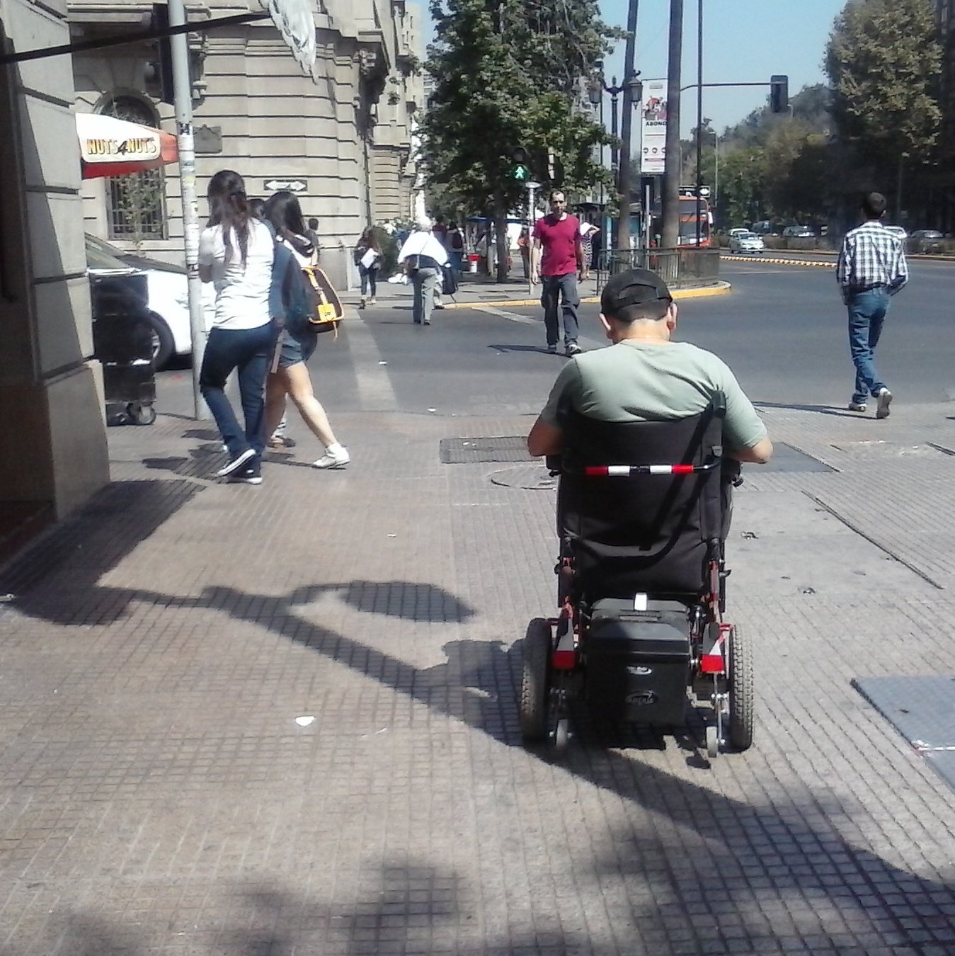 peatón en silla de ruedas circulando por una vereda y enfrentando un cruce