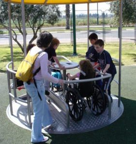 una niña en silla de ruedas comaprte con más niños en un carrusel