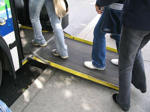 varias personas accediendo al bus por medio de la rampa desplegada en la parte delantera del bus