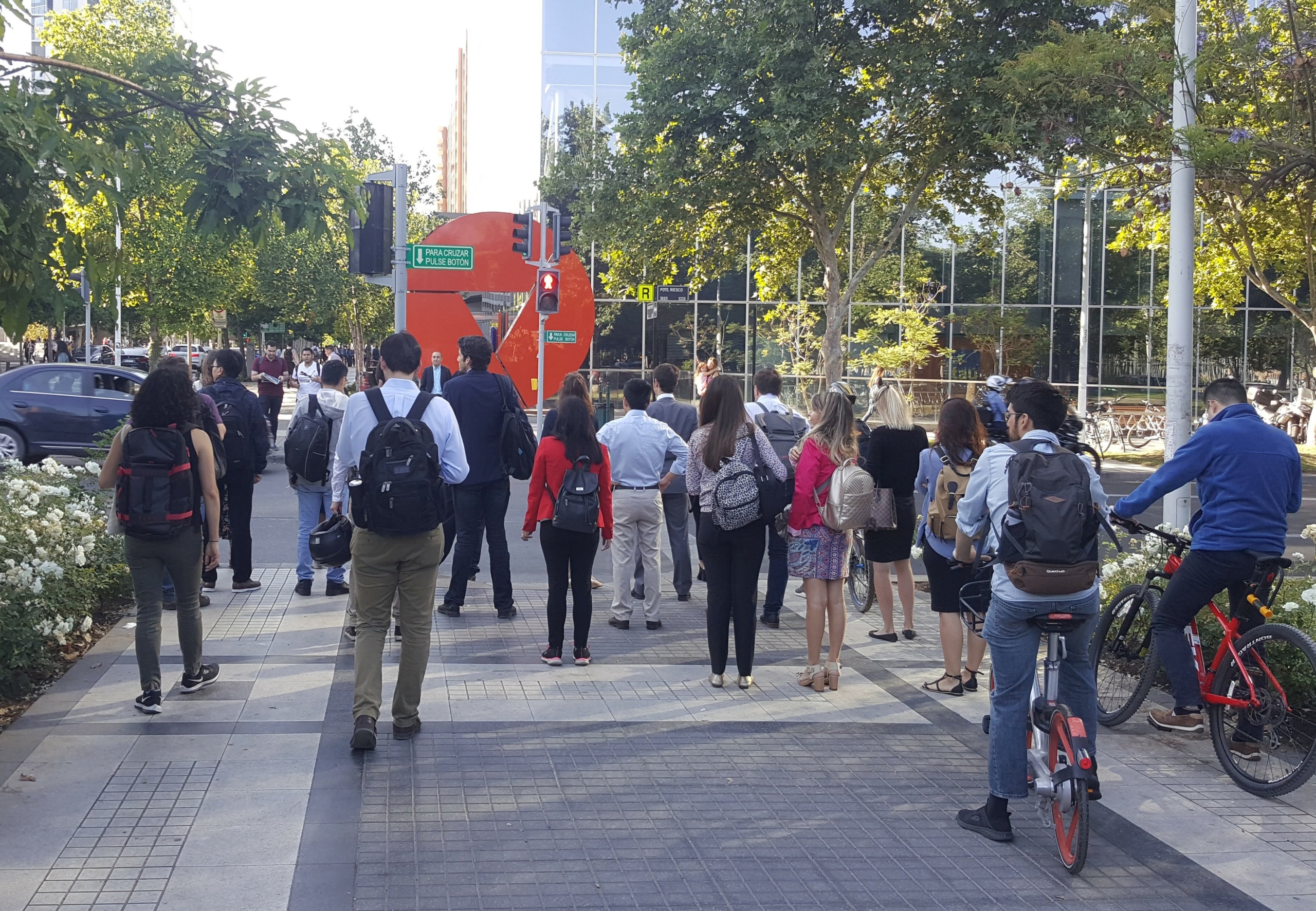 gran cantidad de peatones y varios ciclistas esperando el cruce de la calzada