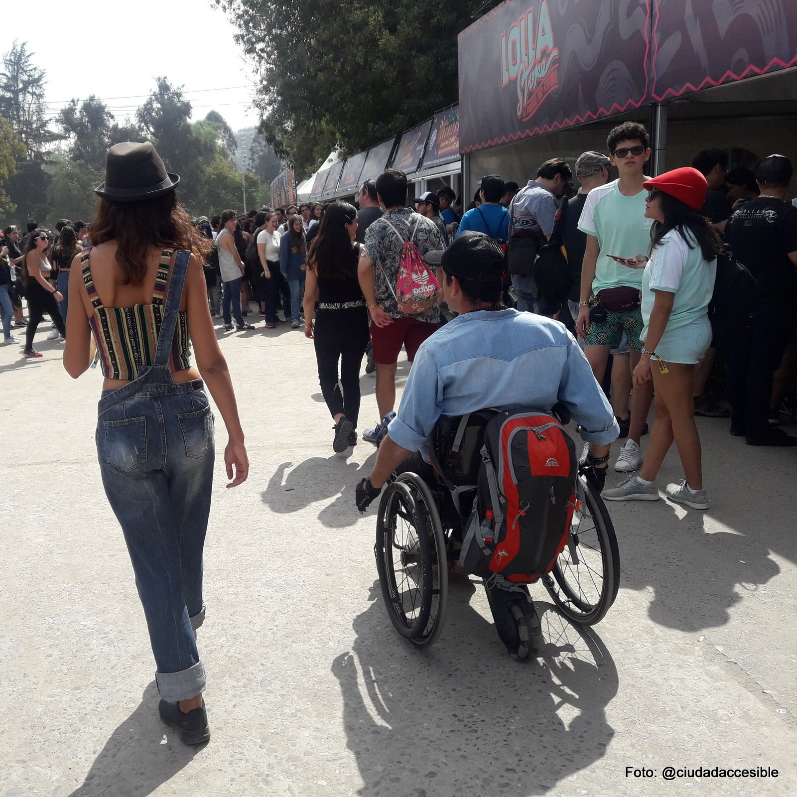 acceso a lollapalooza donde se ve una persona en silla de ruedas acompañada d esu pareja y muchas otras personas entrando al evento