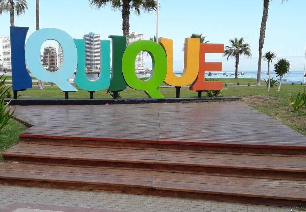 grandes letras de colores ubicadas en un plaza donde se lee la palabra iquique