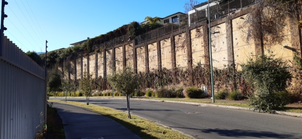 calzada y vereda con una diferencia normal y permanente de diferencia. Se ve un murallón de gran altura y varias casa edificadas en un terreno de pronunciada pendiente.