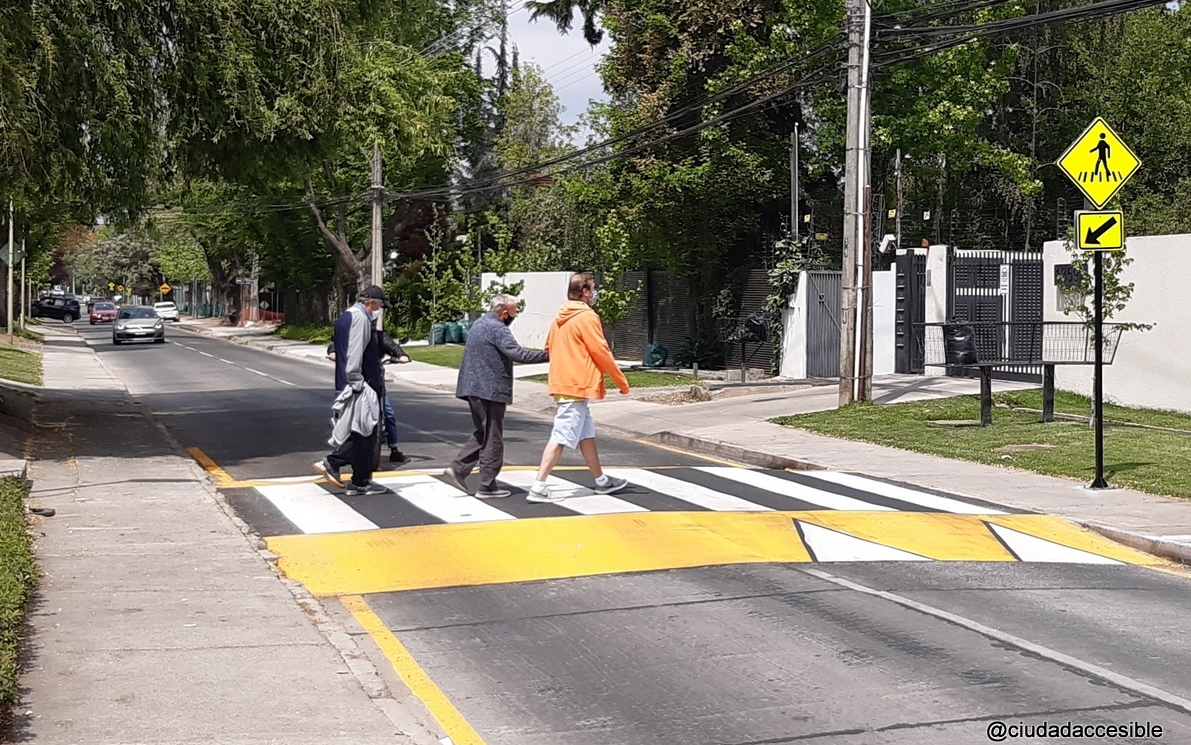 tres personas, una de ellas asistida, cruzan sobre un cruce peatonal continuo a nivel vereda.