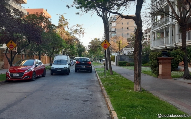 calle angosta de dos sentidos y con autos estacionados en un costado