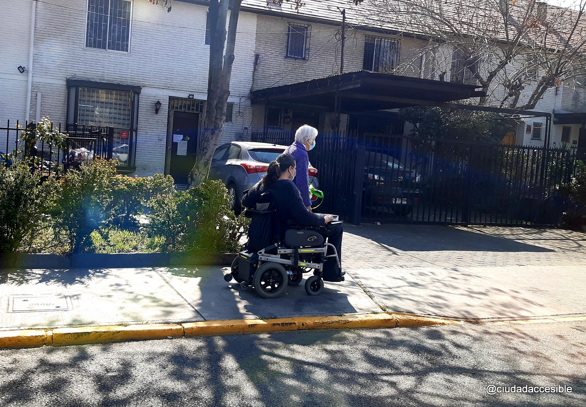 dos personas van por una vereda una de ellas en silla de ruedas