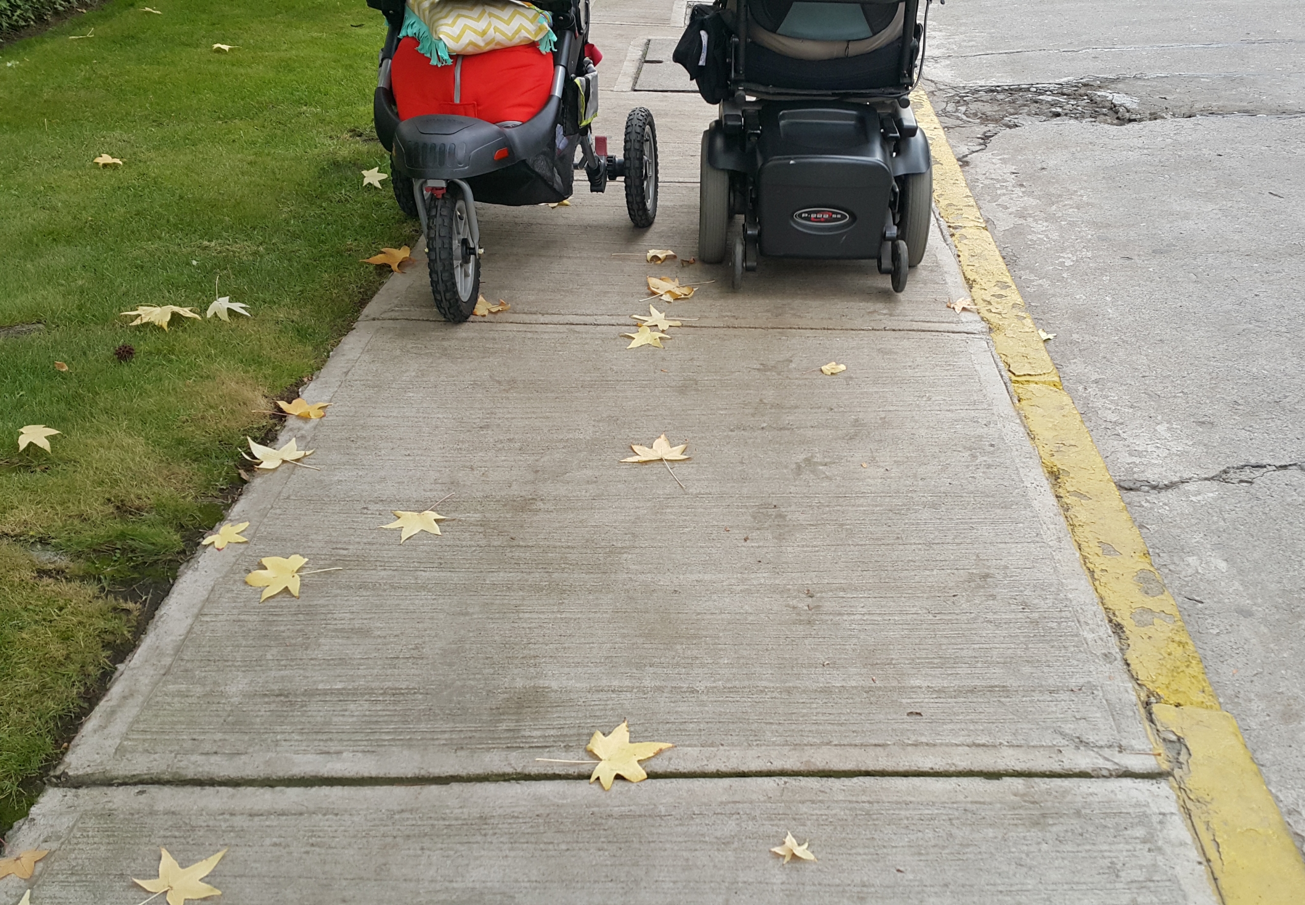 vereda por donde se enfrentan estrechamente una persona en silla de ruedas y otra llevando un coche de niños.