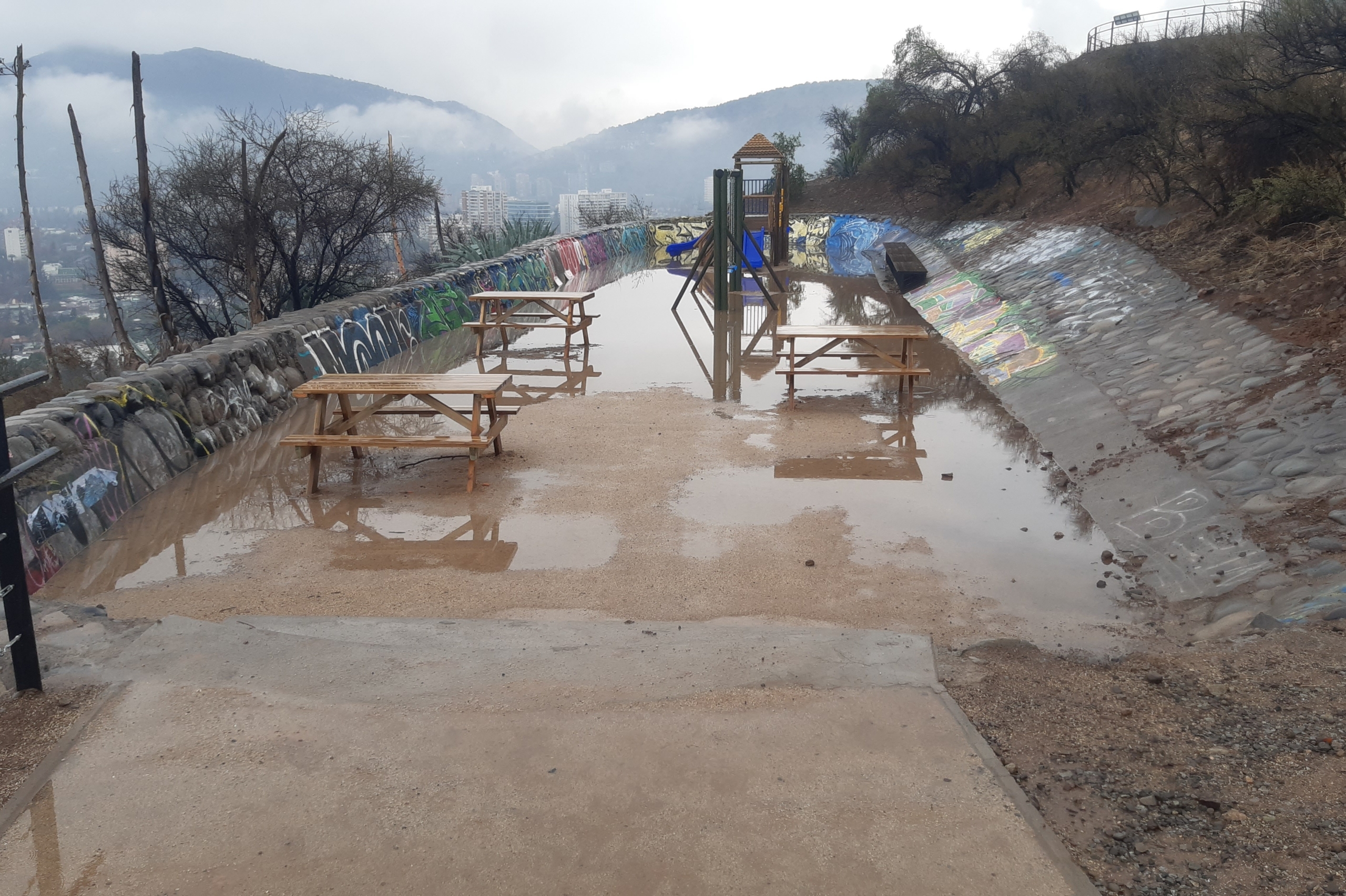 Área de juegos y mesas de picnic acumulando bastante agua posterior a una lluvia