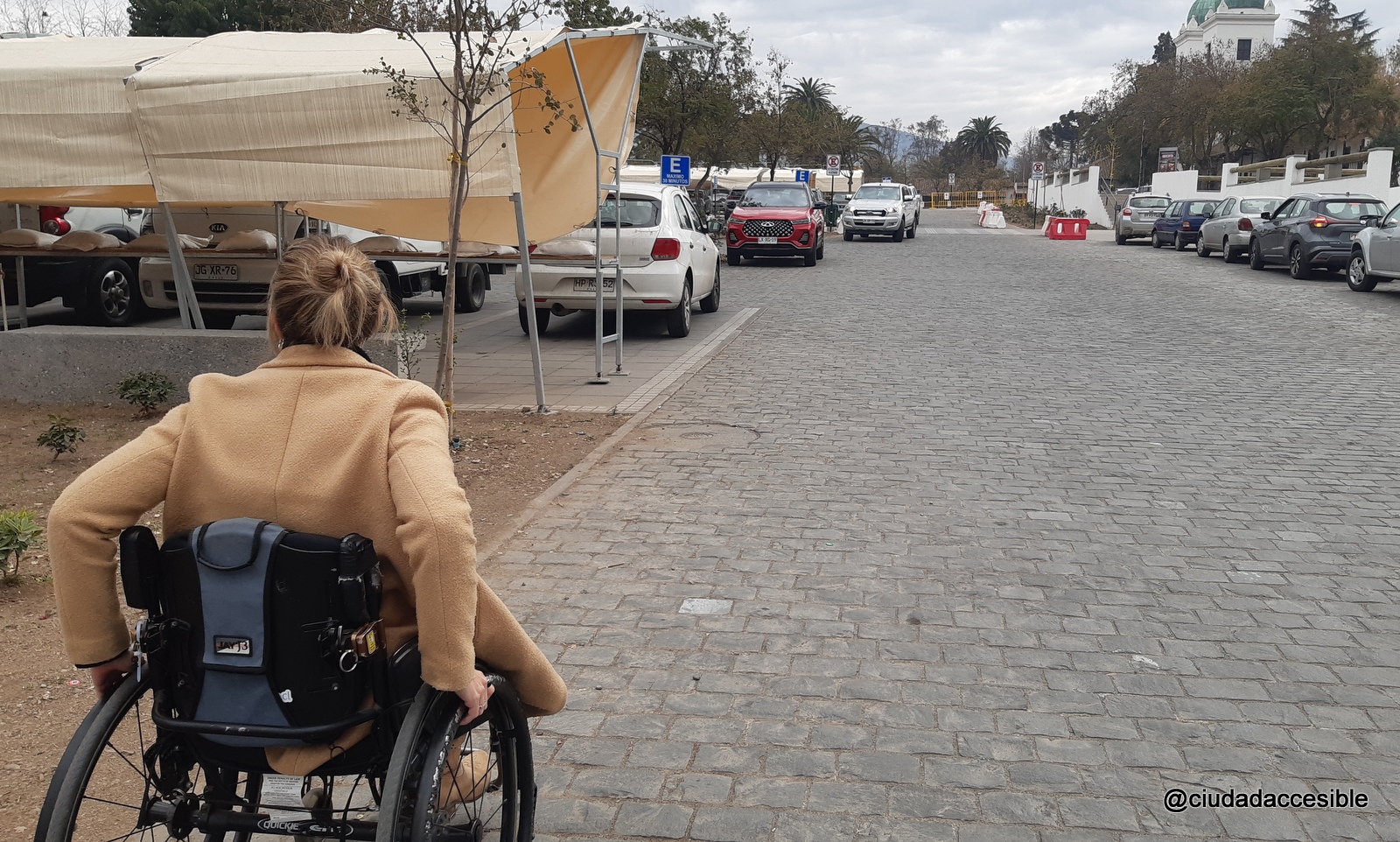Catalina san Martín en silla de ruedas a través de una explanada de adoquines irregulares