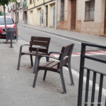 asientos individuales con apoyabrazos en la vereda de una calle de pueblo