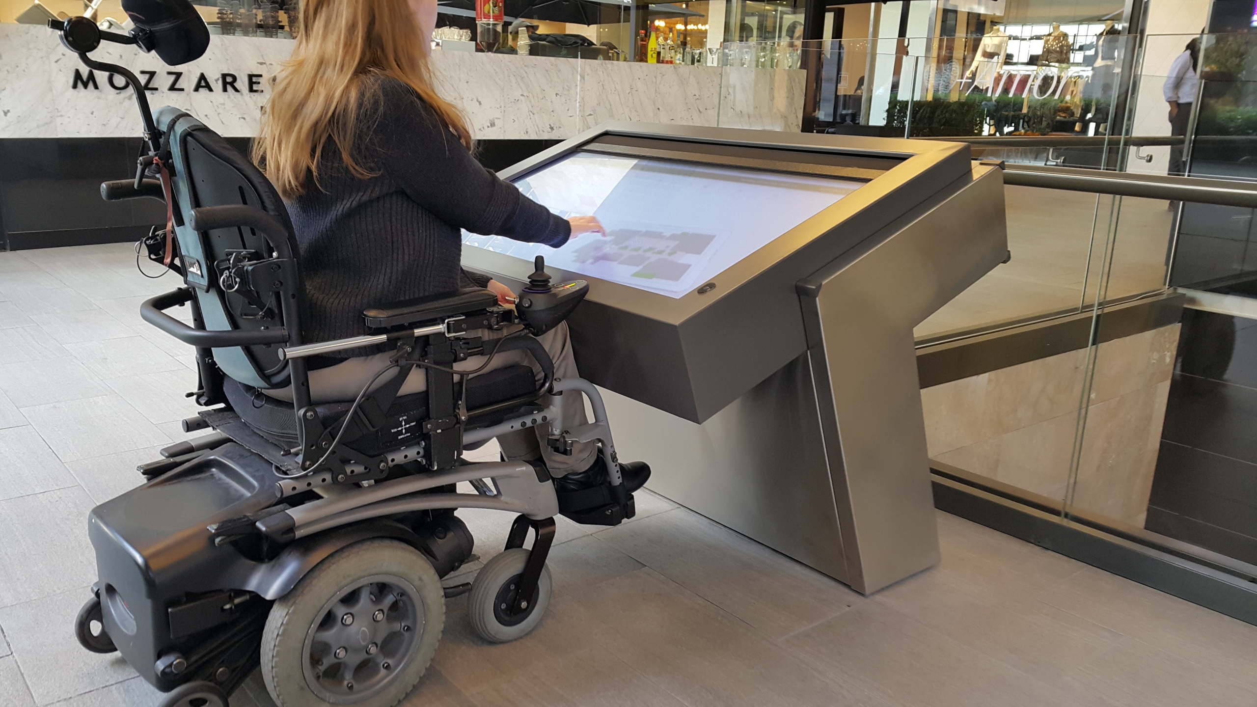 mujer en silla de ruedas consultando un panel de informaciones