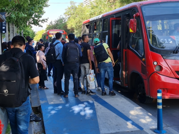 muchas personas esperan la llegada del bus sobre el andén compartido como ciclovía