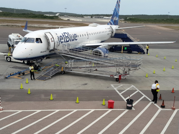 Se ve un avión estacionado en la losa con una rampa de tres tramos adosada a la puerta de embarque.