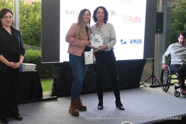 Andrea Legarreta entrega un libro a Javiera Mujica de Red Apis