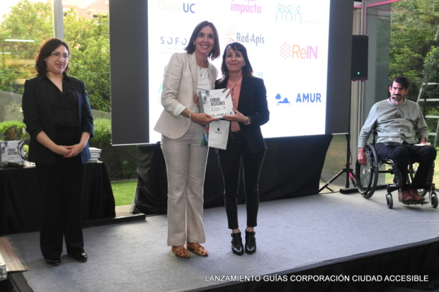 Claudia Riquelme entrega un libro a Macarena Cortés de la Facultad de Arquitectura de la Universidad Católica de Chil