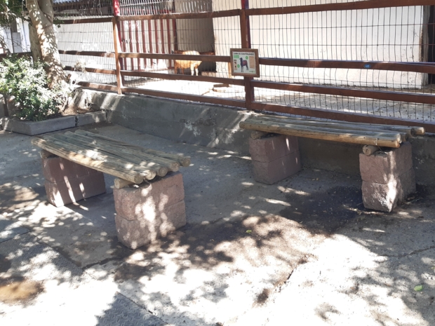 Dos asientos fabricados con rollizos de madera y montados sobre una base de piedra.