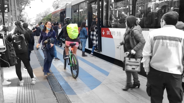 s eve un bus detenido con personas bajando y subiendo en un área que es andén del paradero y a la vez ciclovia.